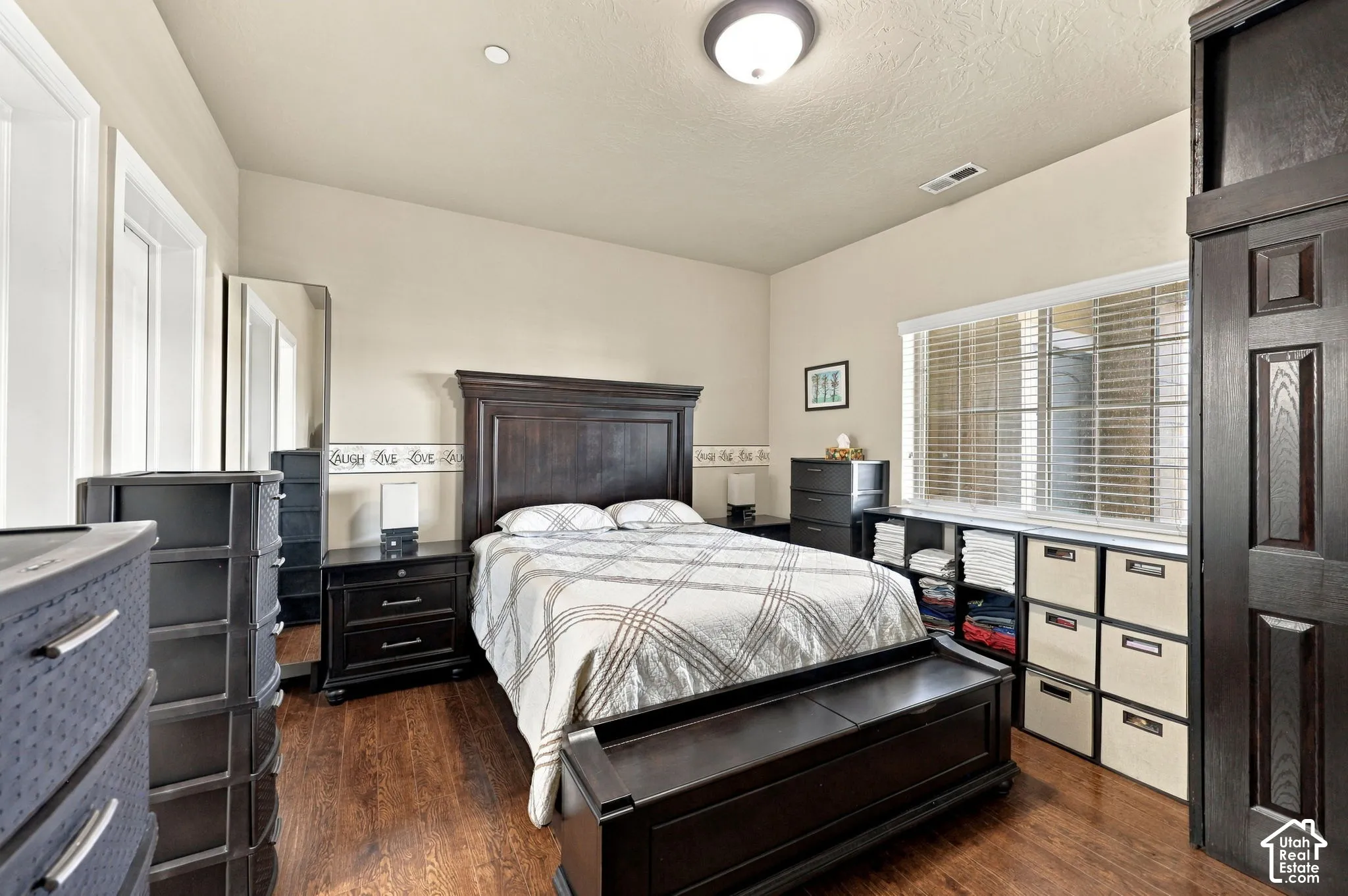 Wood-finish flooring, a window with horizontal blinds, built-in shelving, and a flush-mount ceiling light
