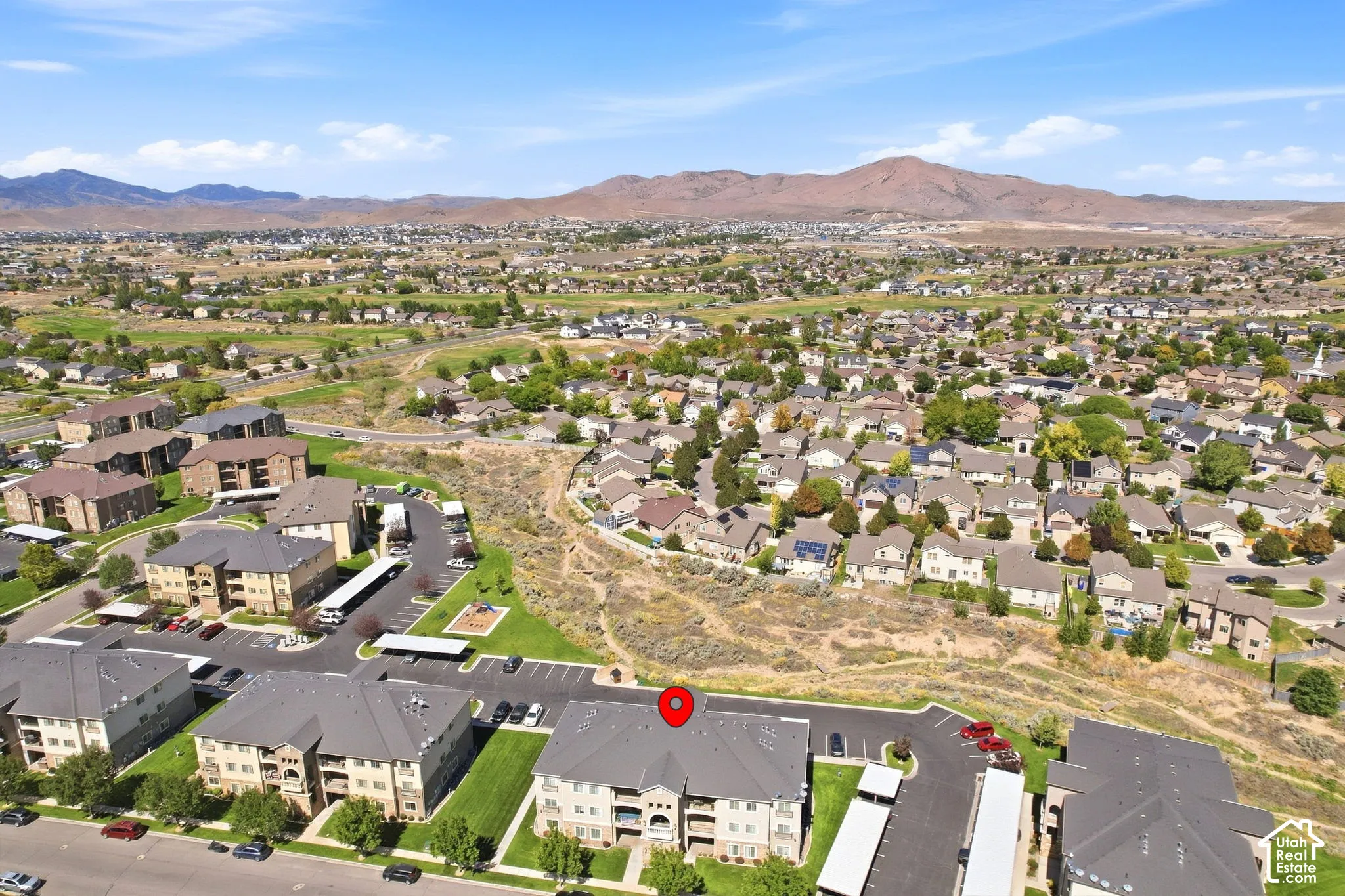 Residential community with multi-story buildings, covered parking, and landscaped grounds against a mountainous backdrop