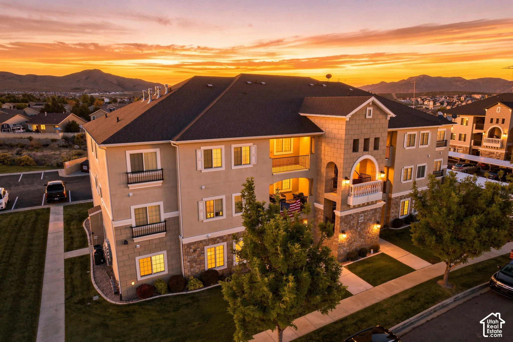 Exterior featuring stone and stucco accents, multiple private balconies with wrought iron railings, and a dark shingle roof