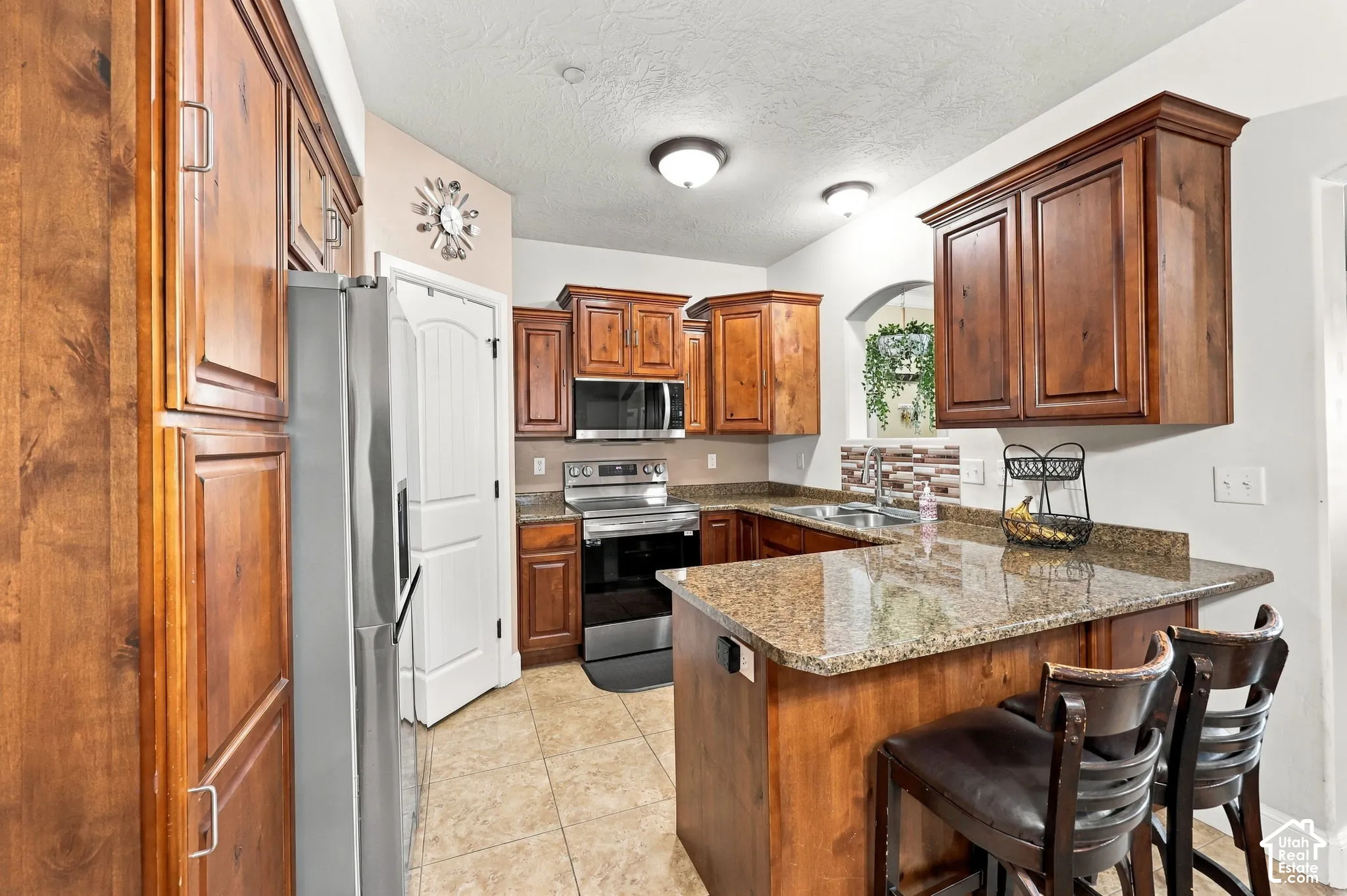 U-shaped kitchen with wood-finish cabinetry, granite-style countertops, stainless steel appliances, and a tiled backsplash