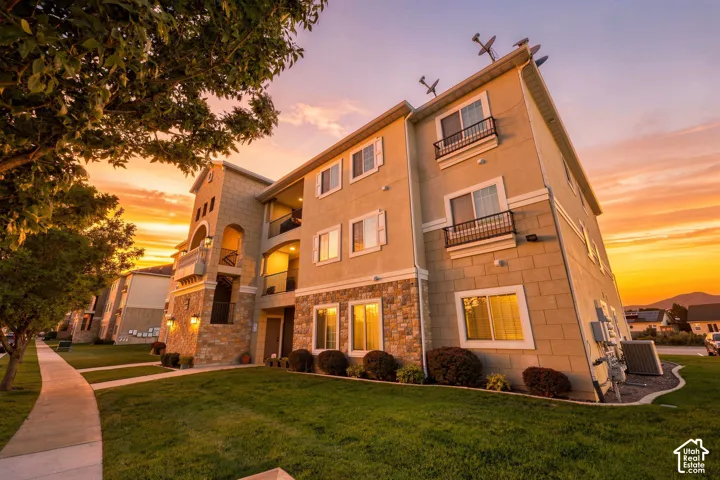 Three-story exterior featuring stone accents, multiple balconies with metal railings, and a side walkway