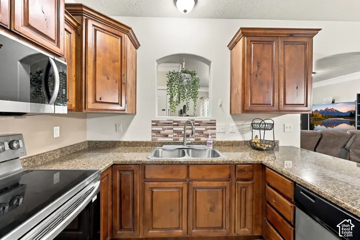 Kitchen featuring wood cabinetry, a double basin sink, and a tiled backsplash