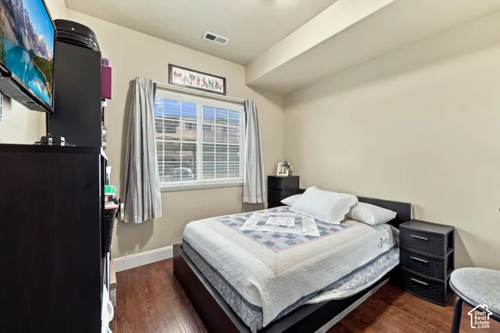 Wood-finish flooring with a window featuring horizontal blinds
