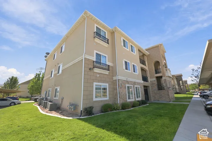 Multi-story building featuring stucco and stone-look siding, individual balconies with iron railings, and multiple windows