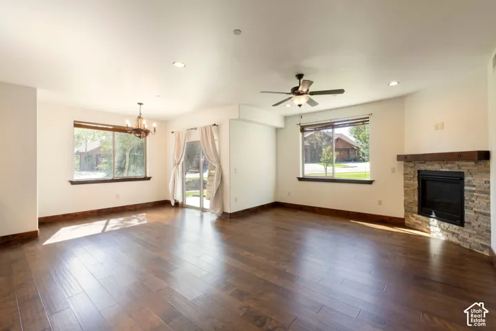 Wood-finish flooring, recessed lighting, and a stacked stone fireplace with a substantial wood mantel