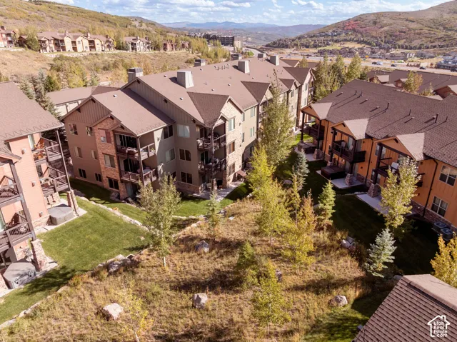 Multi-level property with balconies, varied exterior finishes including brick and siding, and surrounding green spaces with mature trees