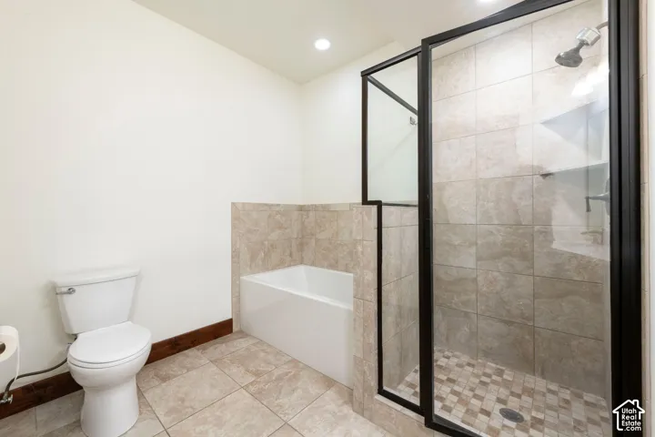 Spa-inspired primary bathroom featuring a freestanding soaking tub, frameless glass walk-in shower enclosure with tile surround, ceramic tile flooring, and dual vanity zones