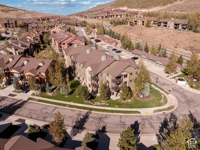 Residential community featuring multi-story buildings, pitched roofs, private balconies, and surrounding natural landscaping