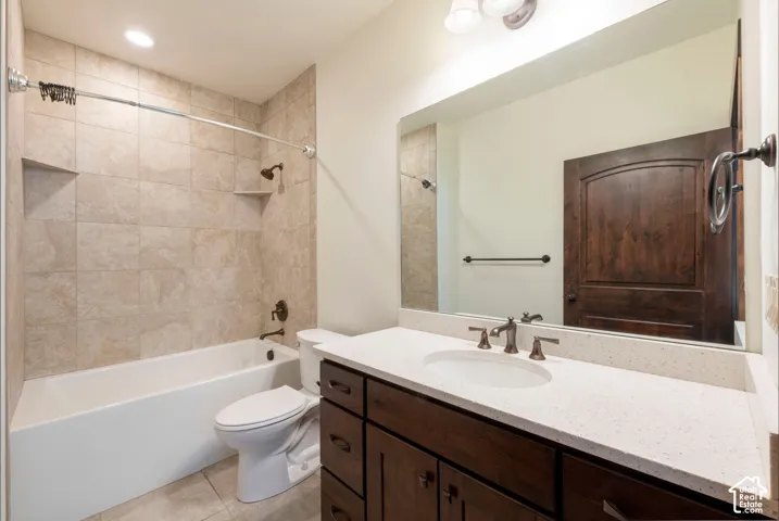 Bathroom featuring a white bathtub, tiled shower surround with built-in niches, dark wood-finish vanity with an integrated sink, white countertop, and oil-rubbed bronze fixtures