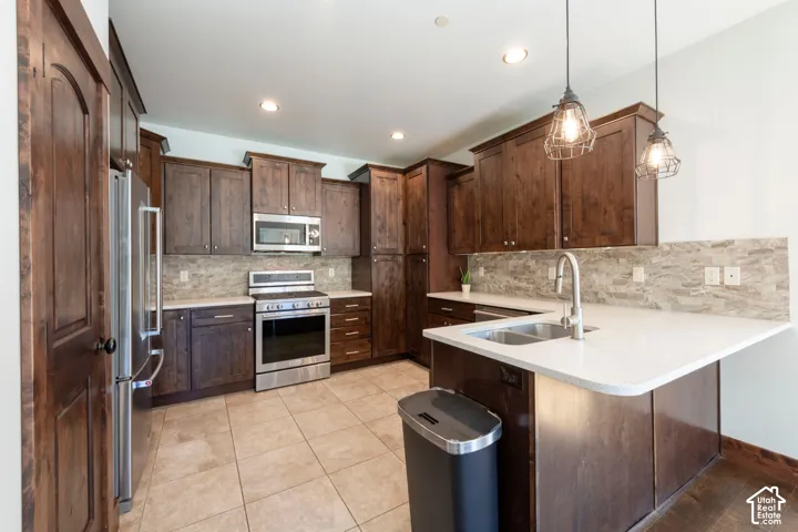Kitchen featuring stainless steel appliances, dark wood-finish cabinetry, tile backsplash, white countertops, and recessed lighting