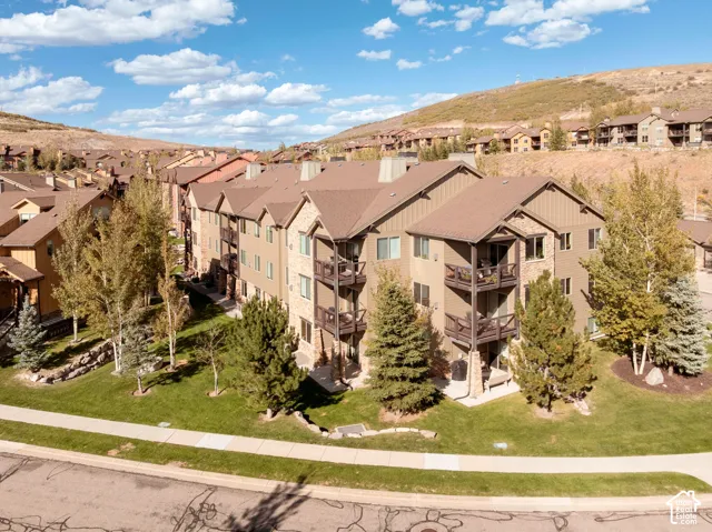 Multi-level structure featuring stone and horizontal siding, individual balconies with dark railings, and a sloped roofline