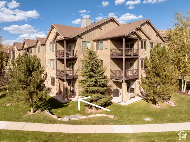Stone and siding facade featuring multiple private balconies, a ground-level patio, and surrounding landscaping