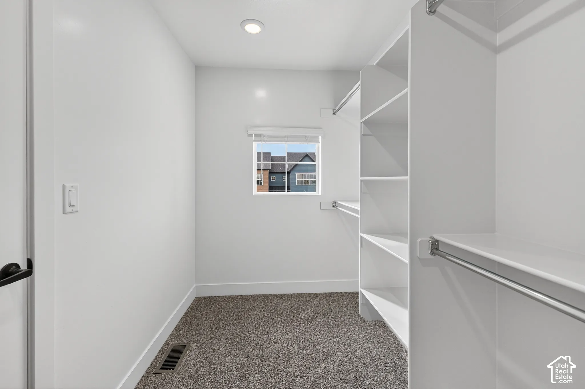 Walk-in closet featuring built-in shelving, hanging rods, recessed lighting, and a window