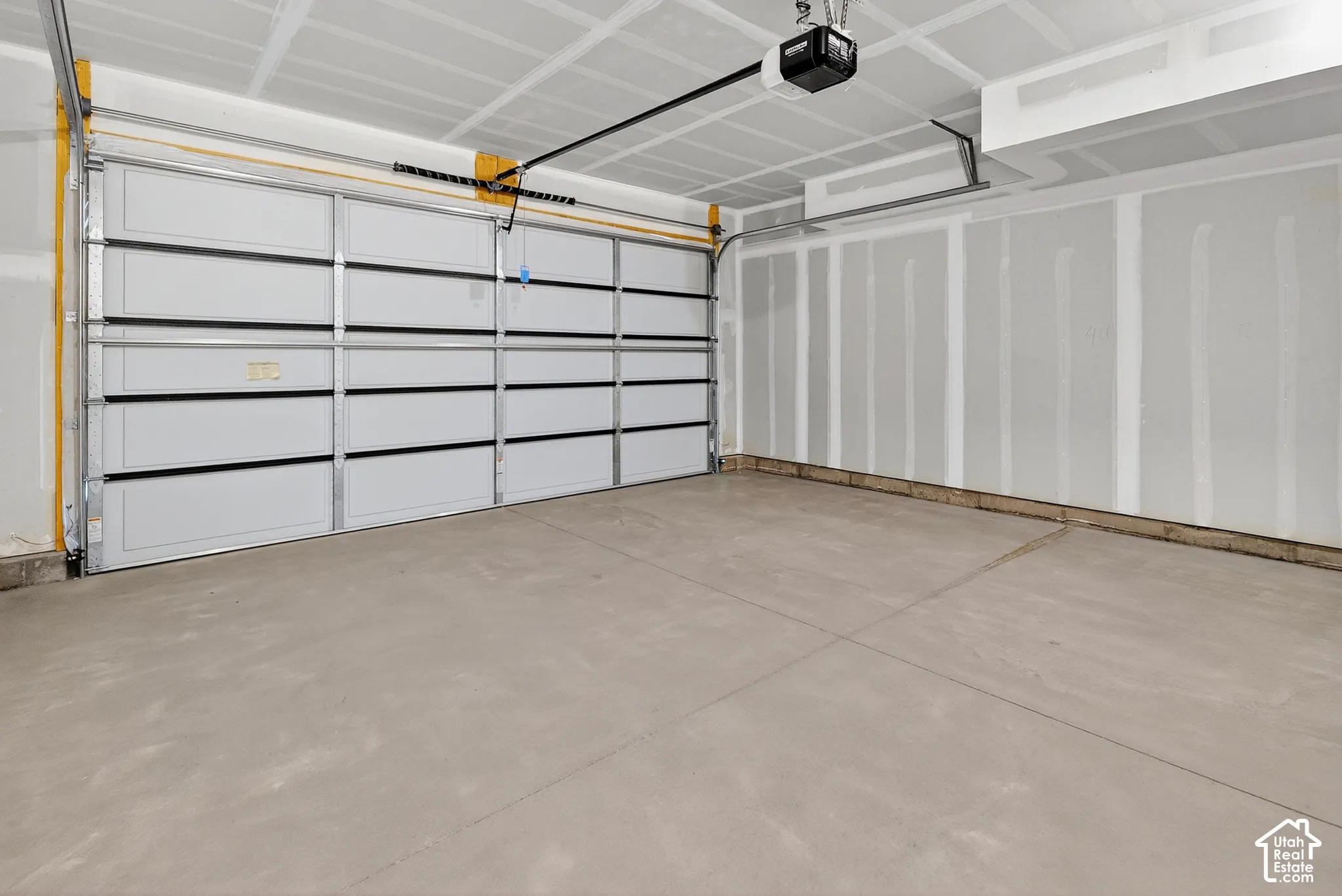 Spacious garage with an automatic overhead door, concrete flooring, and exposed ceiling joists