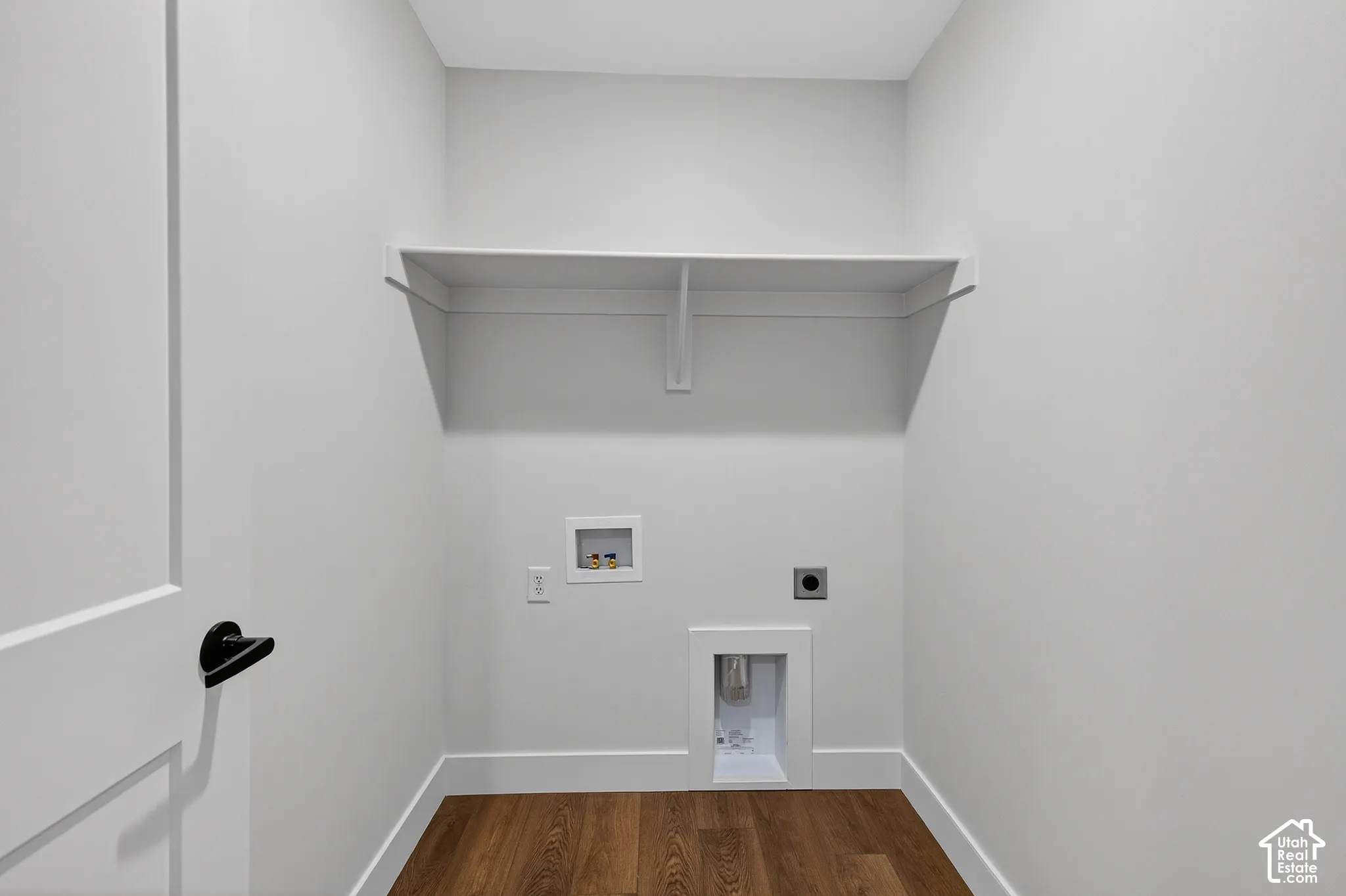 Dedicated utility space featuring wood-finish flooring, white walls, and a built-in shelf