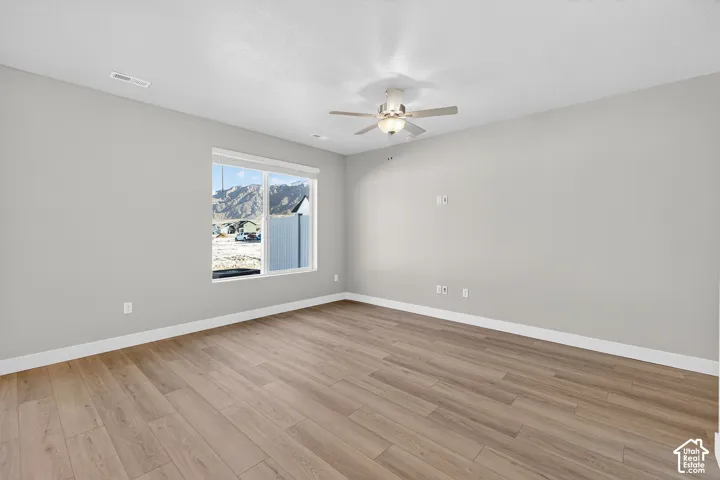 Neutral wall tones, wood-finish flooring, and a ceiling fan with integrated lighting