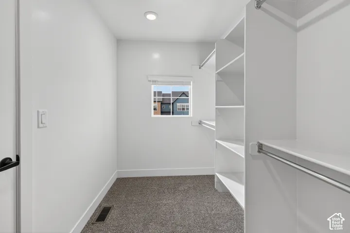 Walk-in closet featuring built-in shelving, hanging rods, recessed lighting, and a window