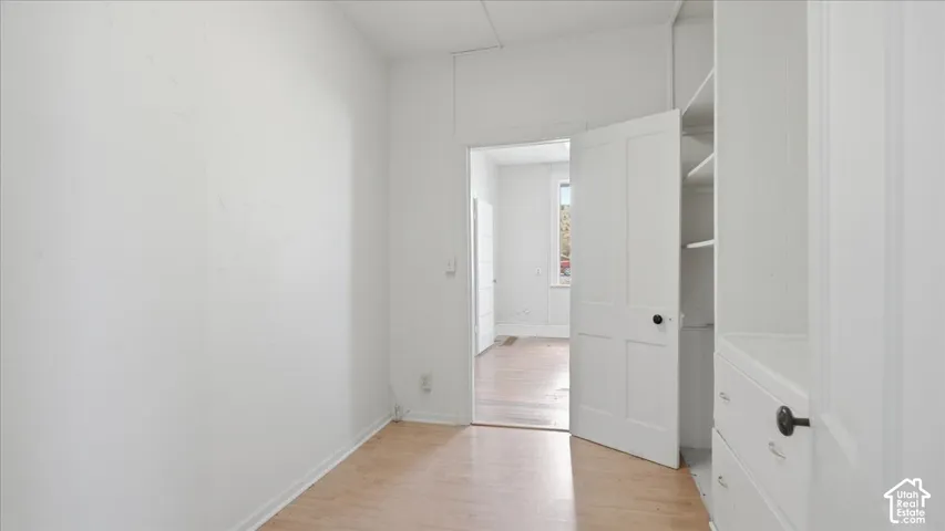 Wood-finish flooring with white walls and a built-in storage unit featuring shelving and drawers