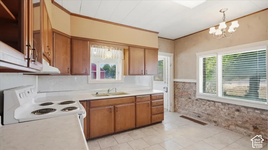 Kitchen featuring wood cabinetry, white countertops, tile flooring, and a brick accent wall