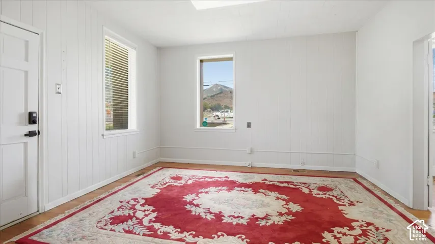 Wood-finish flooring with white paneled walls and multiple windows