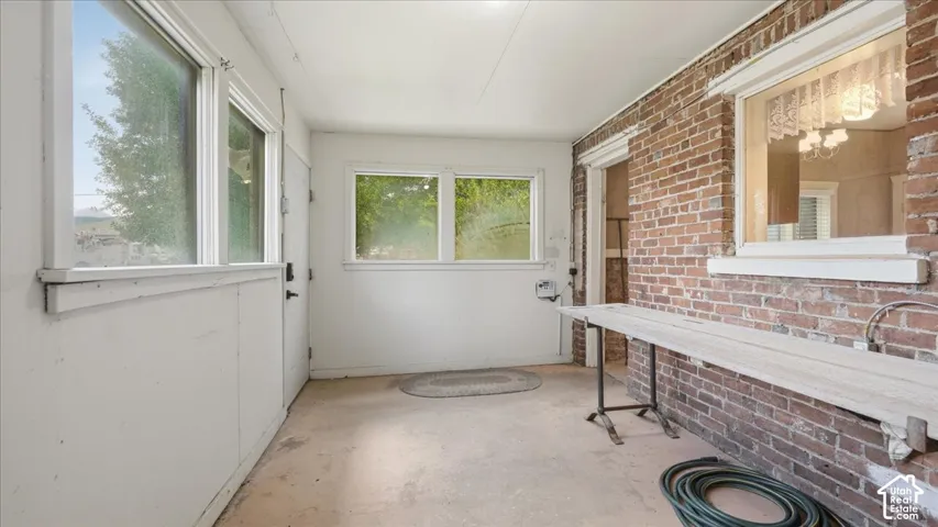 Enclosed porch with exposed brick wall, multiple windows, and a built-in shelf