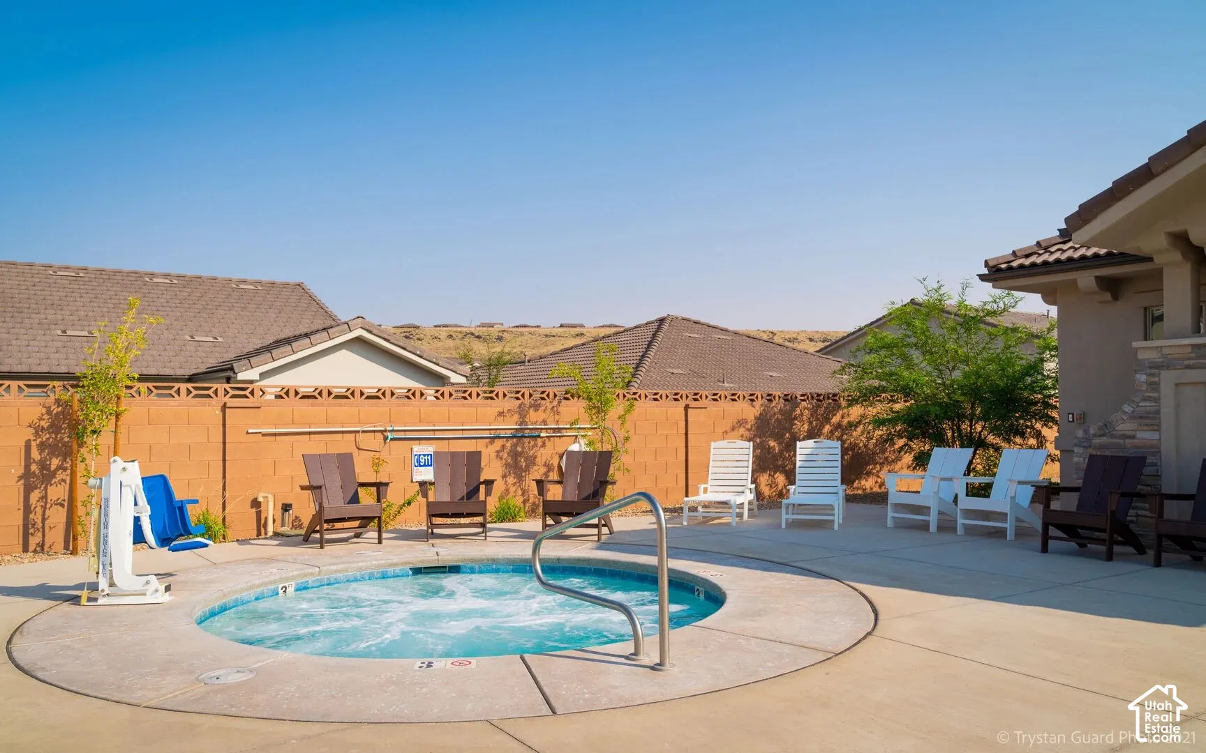 Circular spa with concrete surround, surrounded by a low brick wall, and featuring a built-in outdoor structure with stone veneer detailing