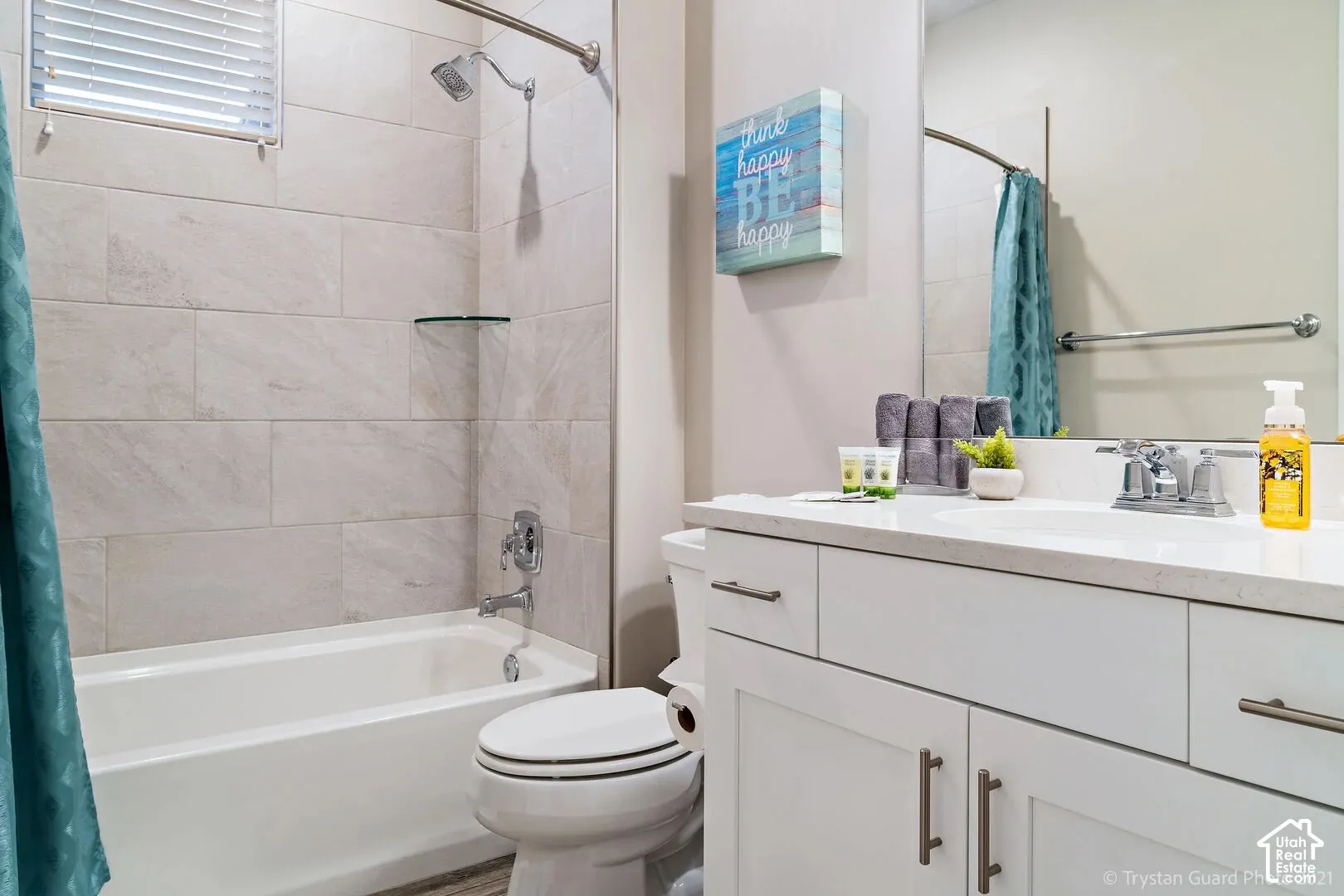 White subway tile shower surround with a built-in tub, chrome shower fixtures, and a white vanity with a light-toned countertop