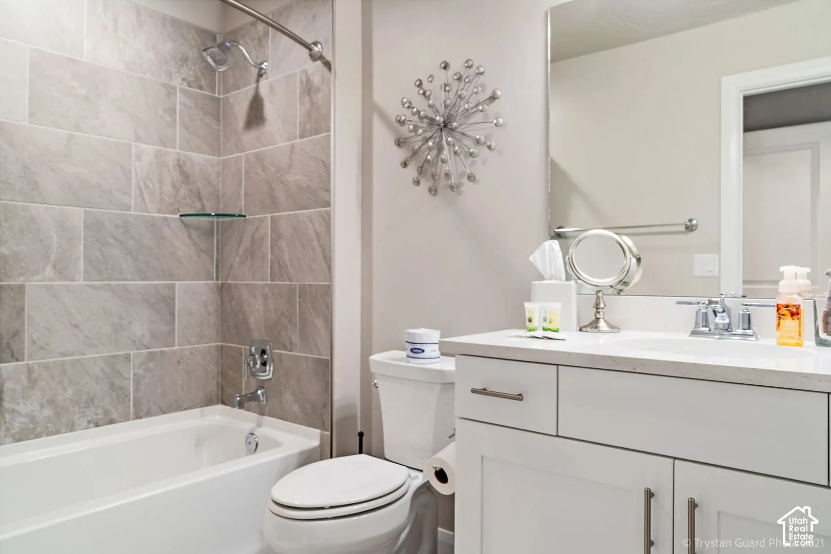 Bathroom with a tiled shower surround, integrated bathtub, and a vanity featuring a white countertop and base cabinetry