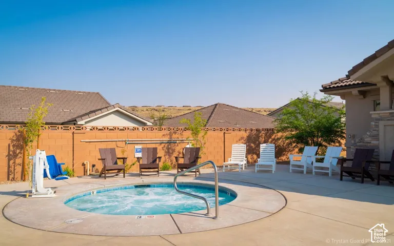 Circular spa with concrete surround, surrounded by a low brick wall, and featuring a built-in outdoor structure with stone veneer detailing