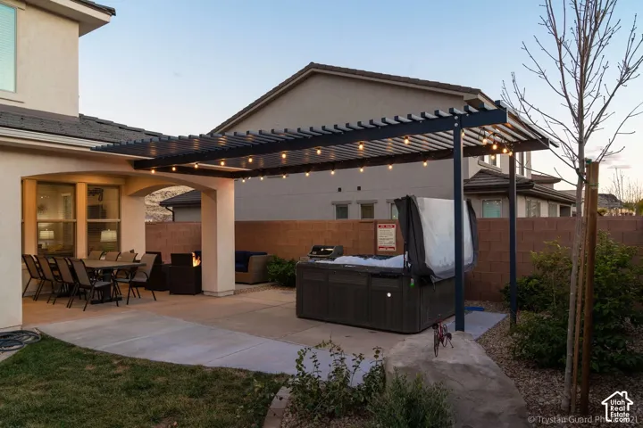 Covered patio with an extended concrete slab, an outdoor grill, and a hot tub under a pergola