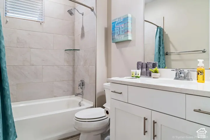 White subway tile shower surround with a built-in tub, chrome shower fixtures, and a white vanity with a light-toned countertop