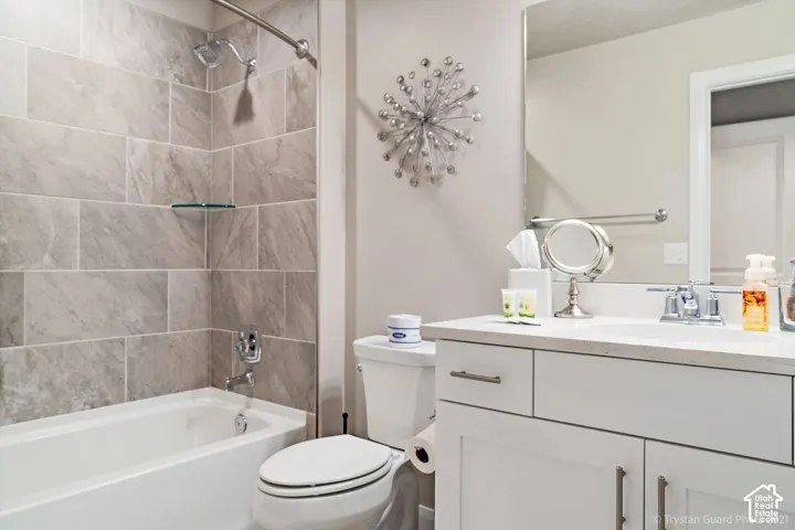 Bathroom with a tiled shower surround, integrated bathtub, and a vanity featuring a white countertop and base cabinetry