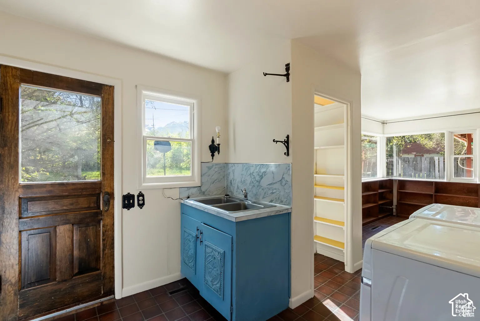 Utility room featuring a double basin sink, detailed cabinetry, tile flooring, and a window for natural light