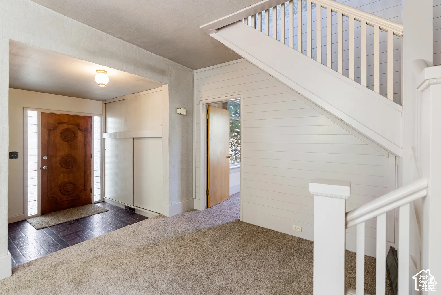 Entry foyer with decorative wood door and sidelight windows, built-in storage, wood-finish flooring, and a carpeted staircase with white railings