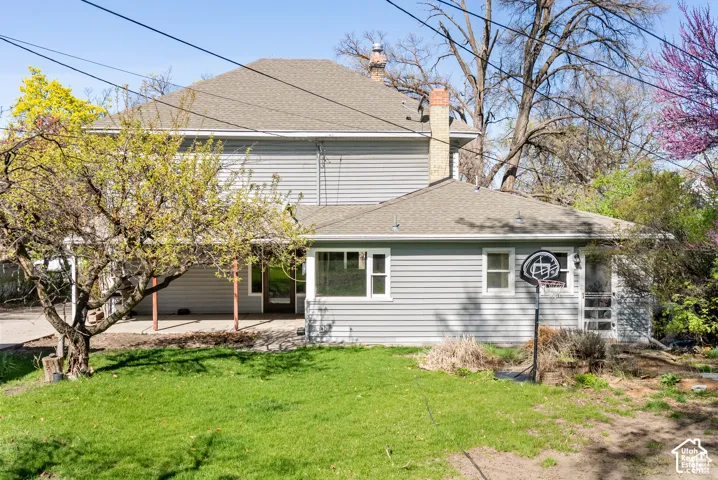 Multi-level home featuring light gray siding, a covered patio, and a shingled roof
