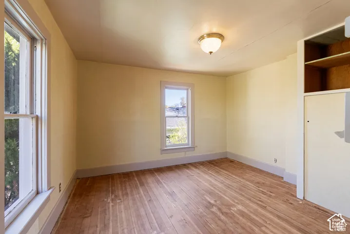Hardwood flooring, two windows, built-in shelving, a ceiling-mounted light fixture, and painted walls