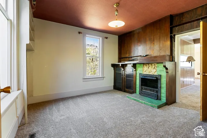 Built-in fireplace with green tile surround and decorative relief, complemented by wood paneling and a suspended light fixture