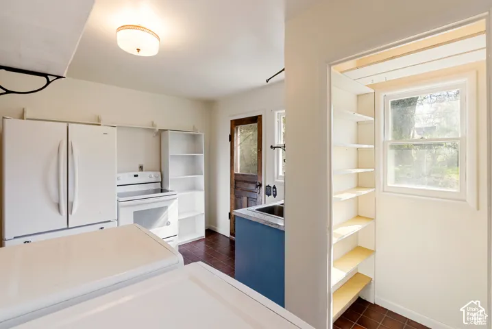White appliances, built-in shelving, durable tile flooring, and a window with natural light