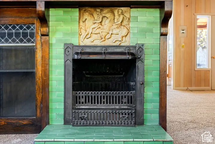 Green tile fireplace surround with an ornate metal firebox and a carved relief panel