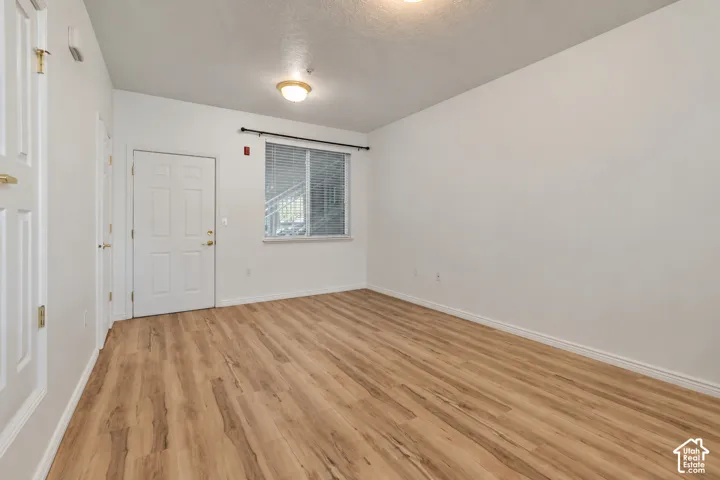 Light wood-finish flooring, white walls, and a window with blinds