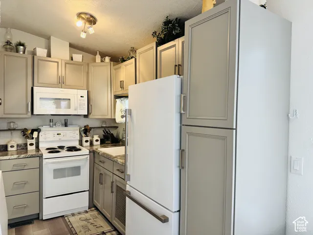 Kitchen featuring light-toned cabinetry, an over-the-range microwave, a white electric range, and wood-finish flooring