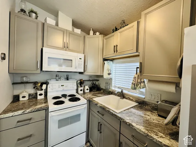 Kitchen featuring an over-range microwave, white electric range, and a single-basin sink