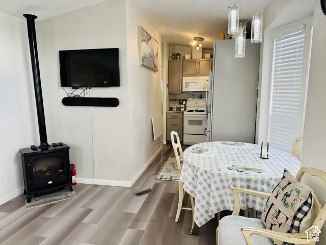 Wood-finish flooring, built-in window blinds, pendant lighting, and kitchen cabinetry with a white range