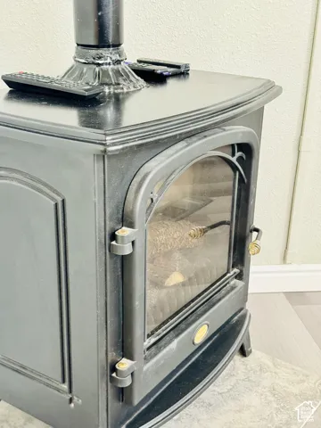 Cast iron wood-burning stove with a glass door and an ornate handle, set on a stone hearth