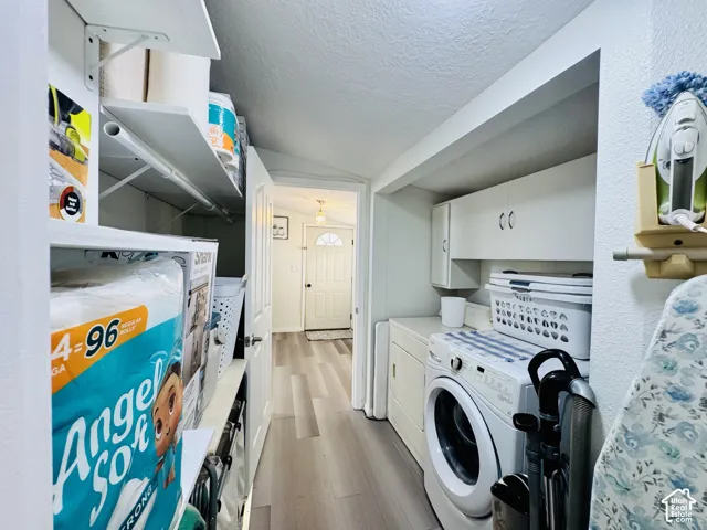 Laundry area featuring built-in shelving, white cabinetry, and wood-finish flooring