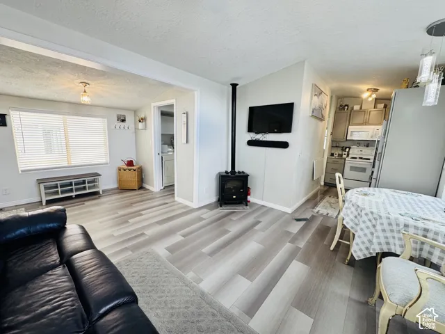 Wood-finish flooring, built-in kitchen cabinetry, built-in range, built-in microwave, and a black wood-burning stove