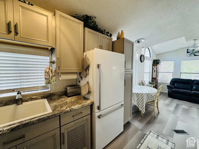 Kitchen featuring painted cabinetry, an undermount sink, and stone countertops