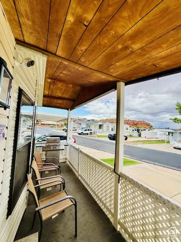 Covered front porch featuring a wood-finish ceiling, vinyl siding, and a lattice railing