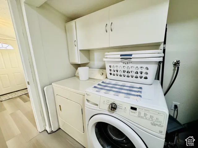 Laundry area featuring upper cabinetry, wood-finish flooring, and a solid white door