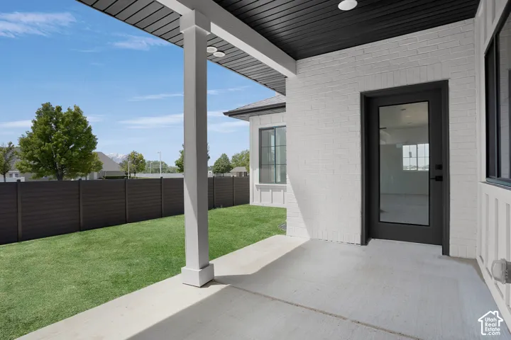 Slate Private backyard - south facing -Covered patio with a concrete slab, white brick exterior, and a dark-framed glass door